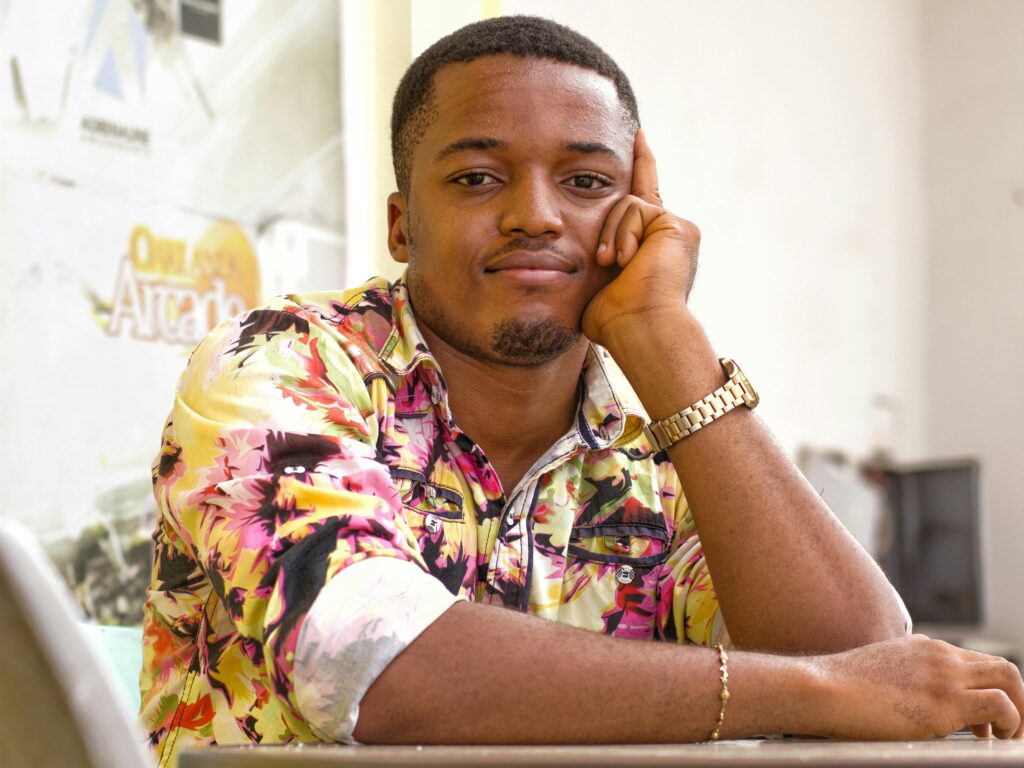 pexels-photo-2327283-2327283 Young man wearing a colorful floral shirt, posing with a thoughtful expression indoors.