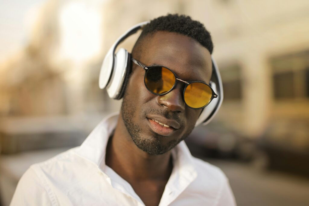 pexels-photo-3758117-3758117 Close-up portrait of a stylish man wearing sunglasses and headphones in a casual white shirt.